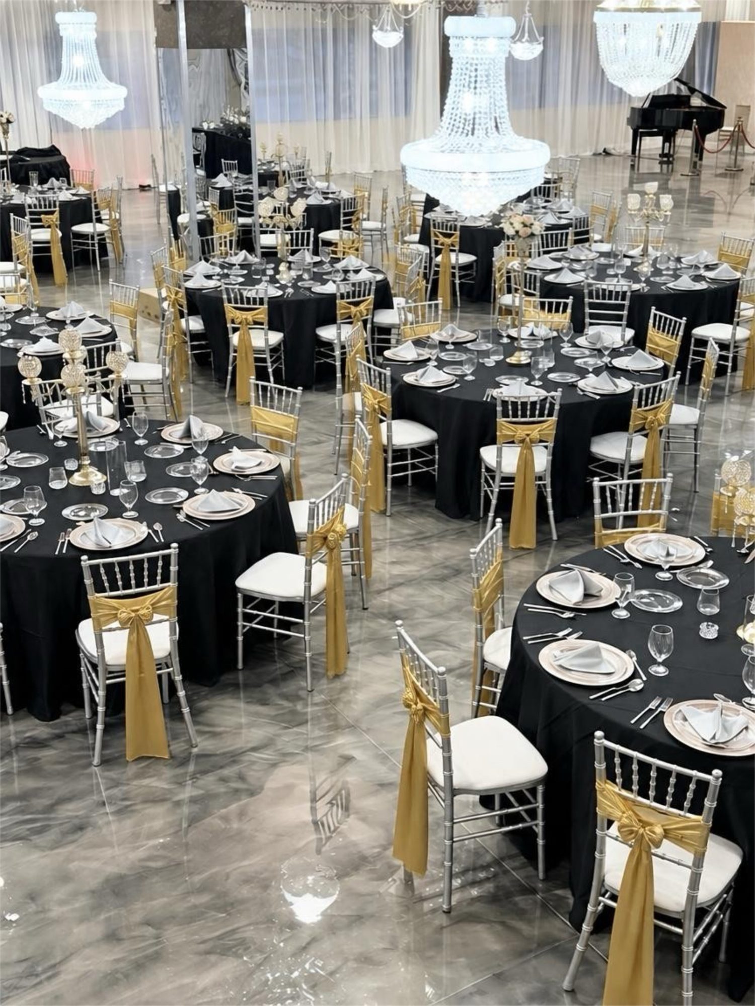 Black linens and gold sashes under crystal chandeliers